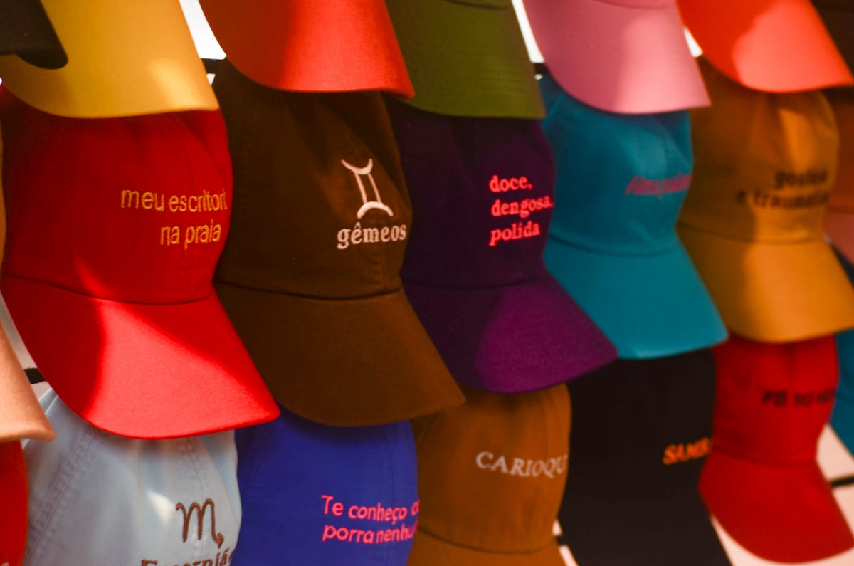 Colorful caps with embroidered text and symbols displayed.